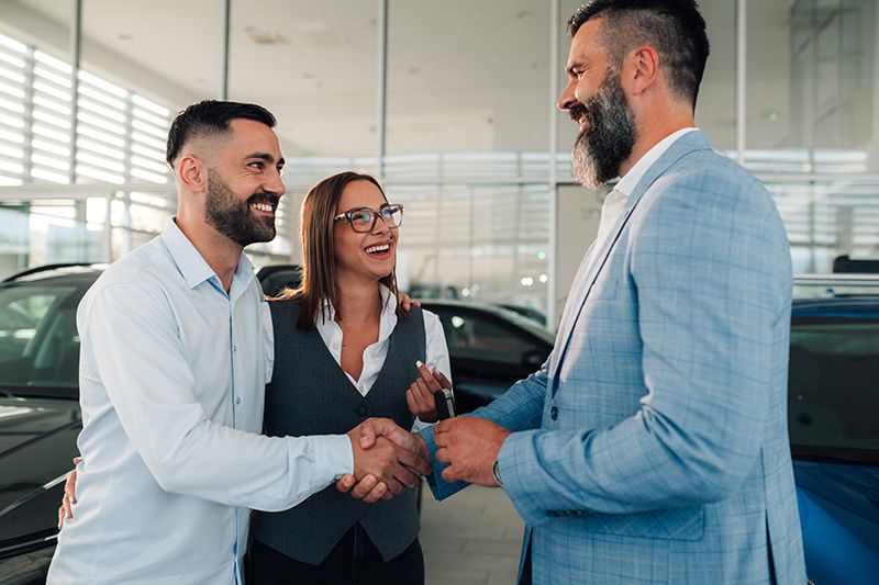 couple-laughing-with-car-dealer-during-successful-2026-01-09-09-21-38-utc.jpg