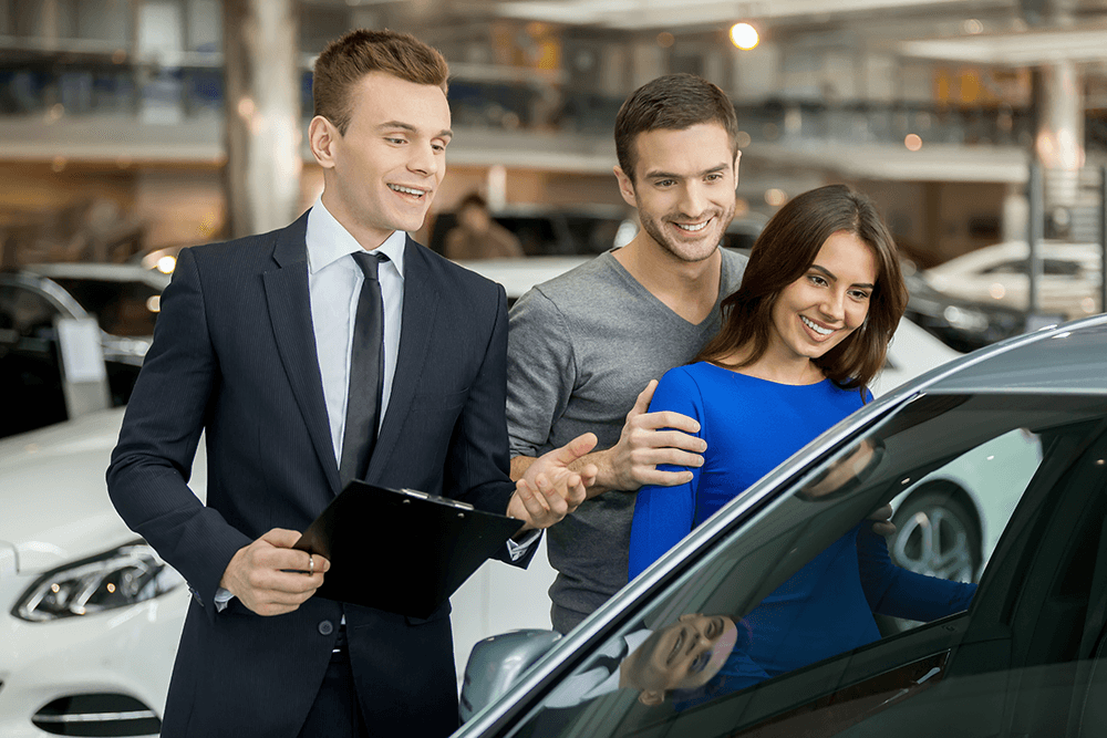 smiling-couple-buying-new-car-from-salesman-2026-01-08-06-00-58-utc.png