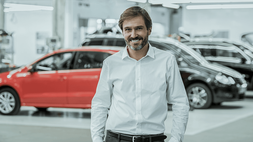 smiling-man-stands-in-car-dealership-showroom-2026-01-07-00-04-56-utc.png